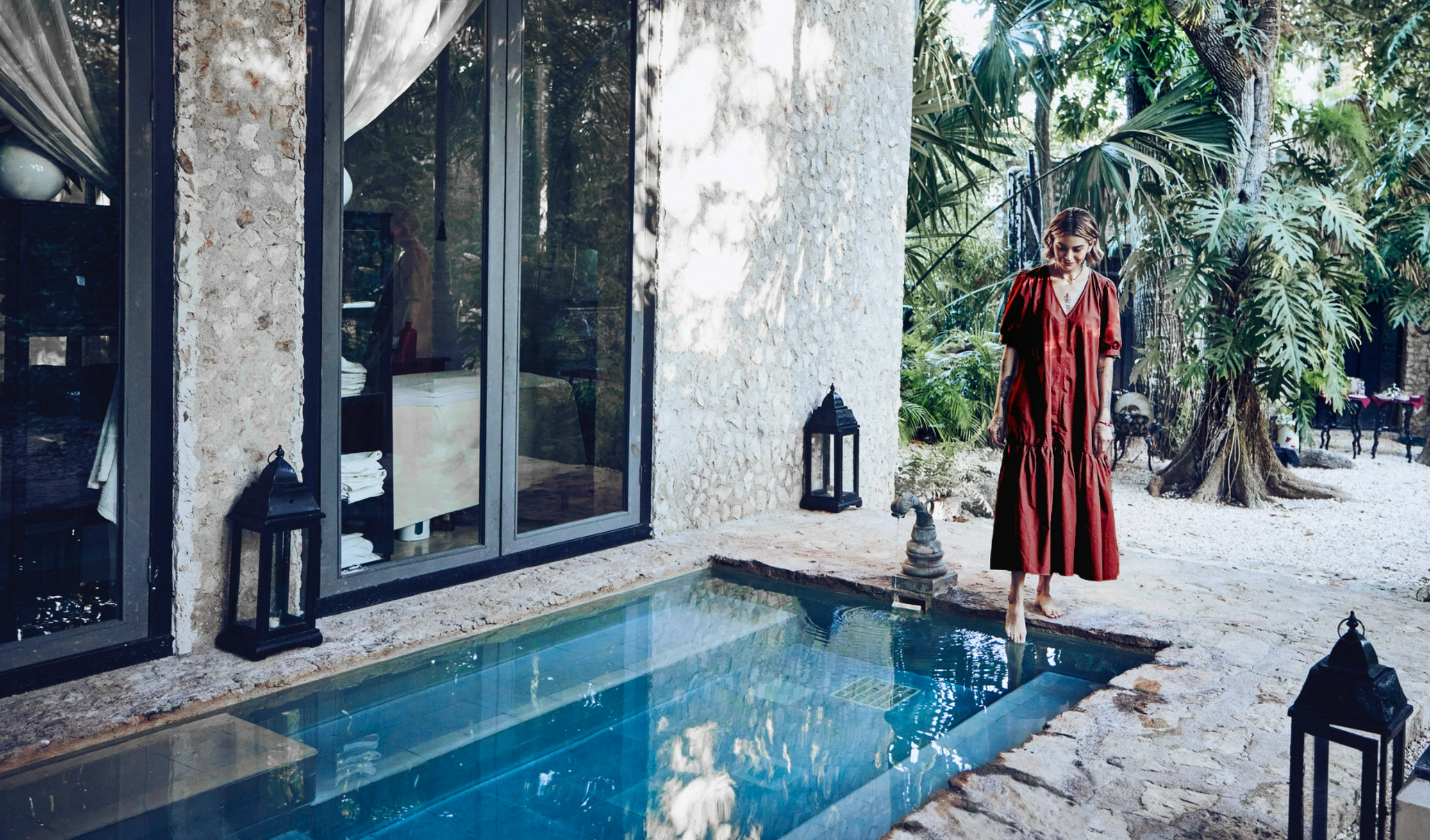 #BradescoAcessivel #ParaTodoMundoVer: mulher colocando o pé na piscina em um cenário paradisíaco.
