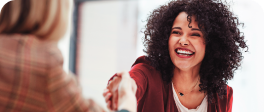 Duas mulheres apertando as mãos sorrindo, uma de frente e uma de costas